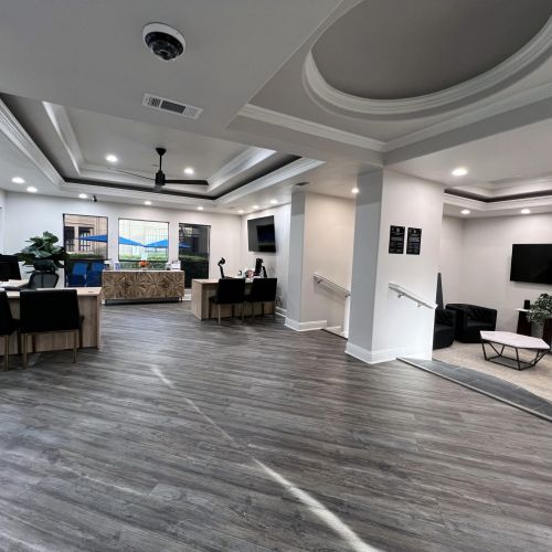Ashwood Park spacious modern office lobby with desks, chairs, large windows, wood flooring, and recessed lighting.