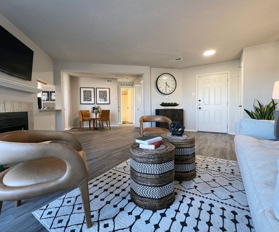Ashwood Park modern living room with wooden chairs, patterned rug, round tables, wall clock, and dining area in background.
